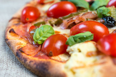 Close-up of fresh cherry tomato slices on pizza over jute