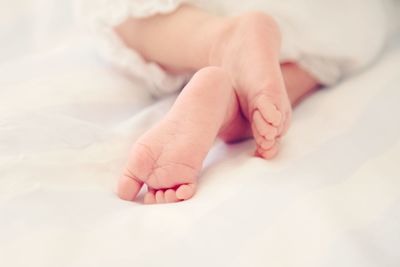 Low section of baby lying on bed