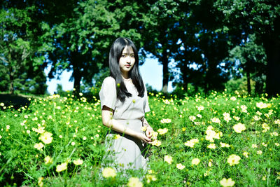Young woman standing by flower tree on field