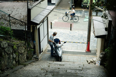 High angle view of man with motor scooter by road