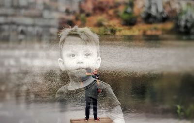 Full length of boy holding umbrella standing in lake during rainy season