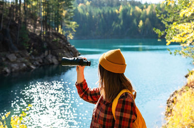 Rear view of woman standing by lake