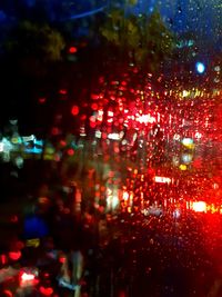 Cars on illuminated street seen through wet windshield