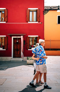 Rear view of man walking on footpath against building