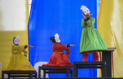 Woman with arms outstretched standing against blue wall