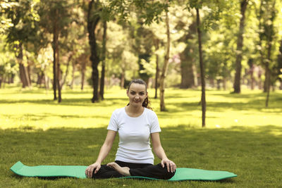 Young woman relaxing in a morning on a mat outdoors in a park