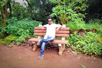 Full length portrait of young man sitting on bench