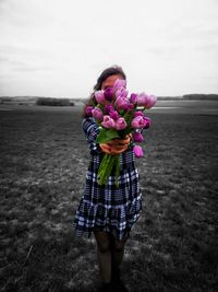 Midsection of woman holding umbrella standing on field