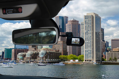 Modern buildings by river in city against sky