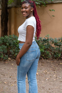 Young woman standing against plants