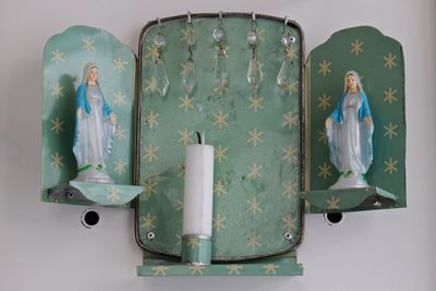 Virgin mary figurines with candle on stand mounted to wall