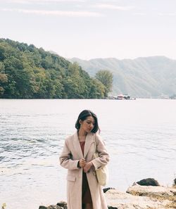 Full length of young woman standing by tree against mountain