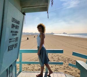 Full length portrait of mature woman standing at lifeguard hut