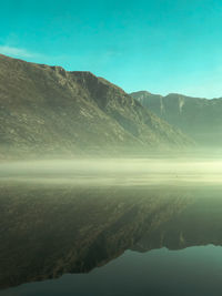 Scenic view of lake by mountains against clear sky