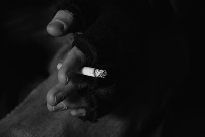 Cropped hand holding cigarette in darkroom