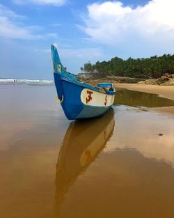 Boat moored on beach against sky