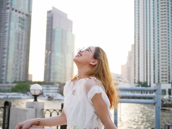 Smiling woman standing against buildings in city