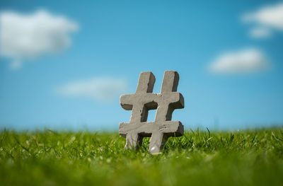 Close-up of cross on field against sky