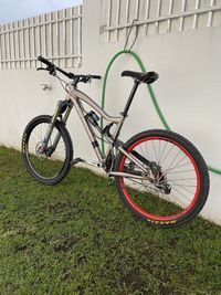 Bicycle parked by railing on field