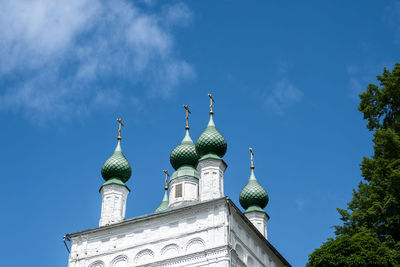 Green domes of the orthodox church with golden crosses on a background of blue sky.