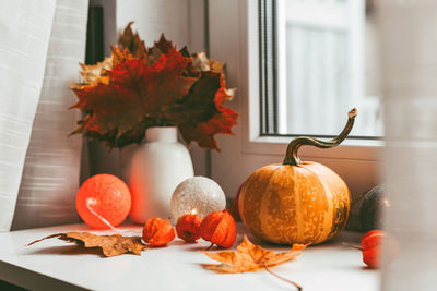 Autumn home decoration on the window using dry leaves and pumpkin