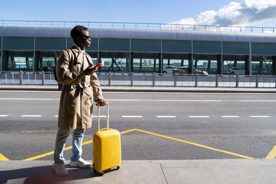 Full length of man with suitcase standing on road