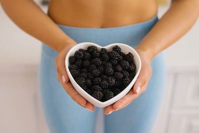 Heart-shaped plate with blackberries in women's hands. the concept of healthy eating