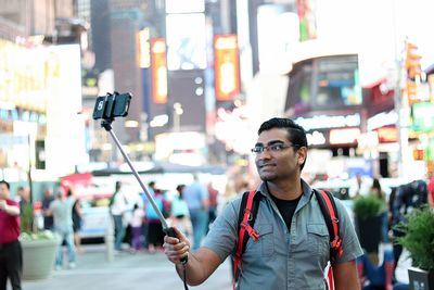 Young woman photographing with mobile phone standing in city