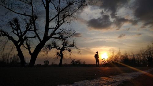 Silhouette man standing on road against sky during sunset