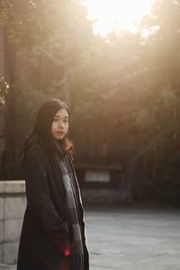 Young woman standing against trees at park