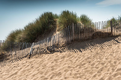 Fence on beach against sky