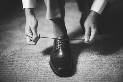 Low section of man tying shoelace on carpet