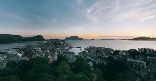 Panoramic view of sea and buildings against sky during sunset