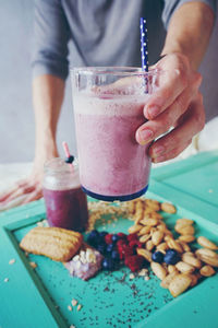 Midsection of man holding drink over table