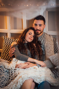 Portrait of young couple sitting on sofa at home