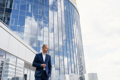 Low angle view of man standing on glass building