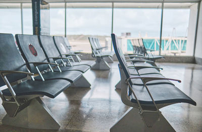 Empty chairs in the departure hall at airport, blurred plane on a background.