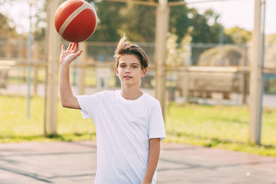 Portrait of boy playing with basketball at court