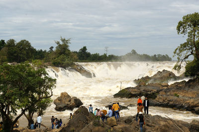 Tourists enjoying on rock against sky