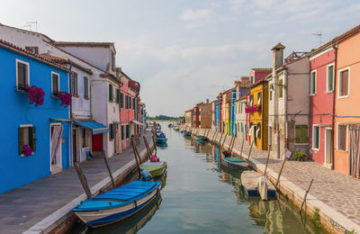 Boats on canal amidst buildings in city against sky