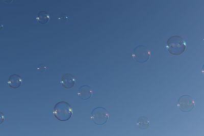 Low angle view of bubbles against blue sky