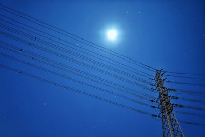 Low angle view of electricity pylon against blue sky