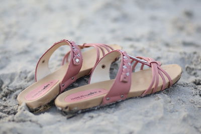 Close-up of footwear on sand at beach