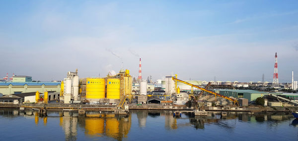 View of factory by river against sky