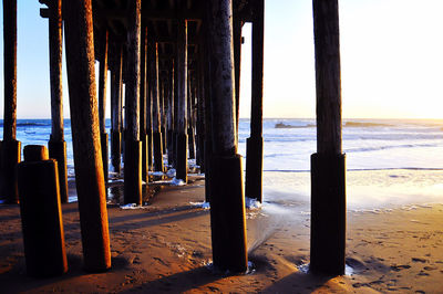 Wooden posts in sea against sky
