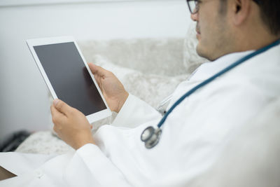 Midsection of doctor holding digital tablet
