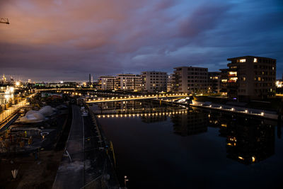 High angle view of illuminated buildings by river against sky
