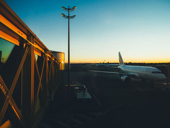 Airplane on airport runway against sky at sunset