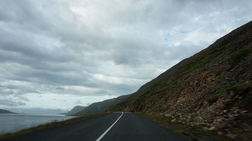 Country road against cloudy sky