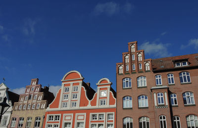 Low angle view of buildings in town against blue sky